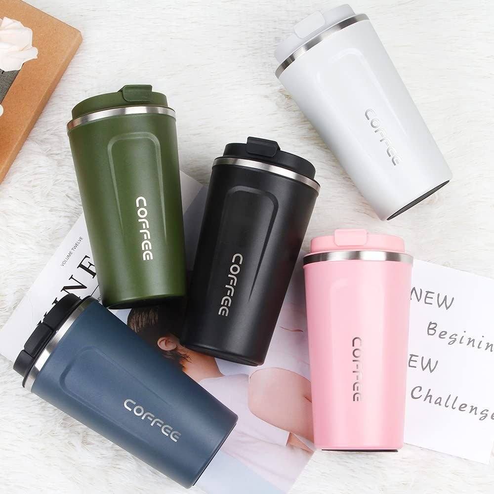 Vacuum insulated stainless steel coffee mugs in blue, black, green, white, and pink displayed on a soft fabric background.