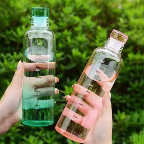 Glass water bottle with time marker pink and blue on wooden table