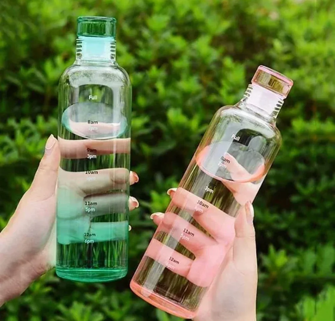 Glass water bottle with time marker pink and blue on wooden table